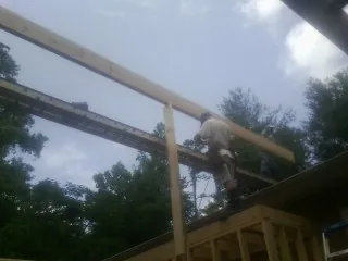 Carpenter setting a ridge beam over a new addition frame — Ice Dam Removal by Roofing Brothers in Sherrard