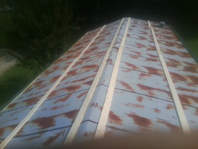 Rusted metal roof panels with new wood purlins before replacement in Sherrard