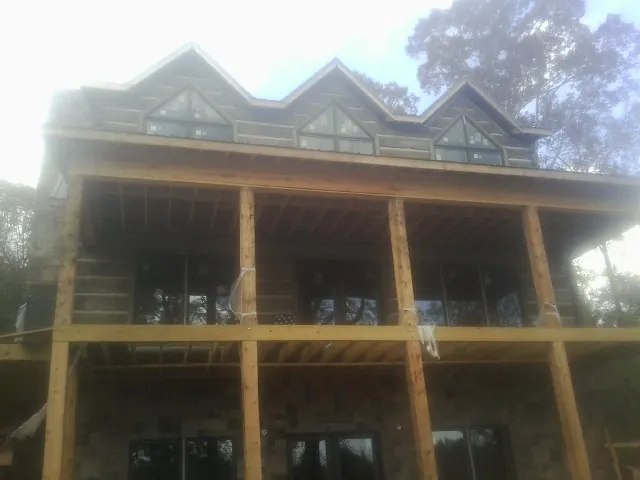 Dormers and porch framing on a large log home under construction — Roof Coating work by our crew in Sherrard