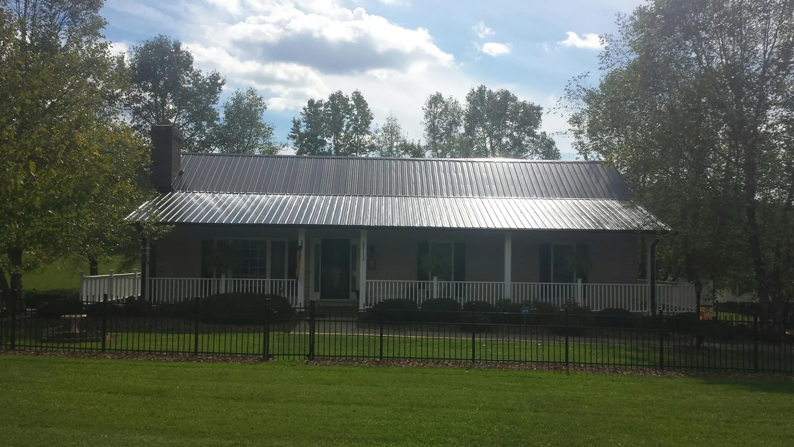 Gray metal roof on a brick ranch with a full width front porch — Gutter Guard Installation work by our crew in Sherrard